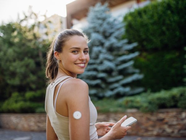 Eine sportliche Frau hat einen Sensor zur Blutzuckermessung beim Laufen.