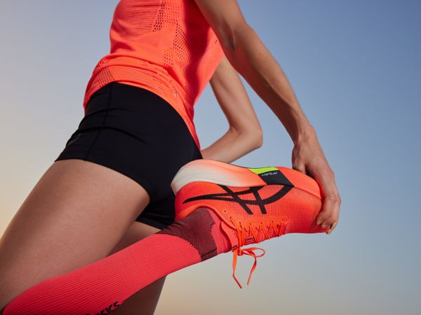 Eine Frau dehnt sich mit dem Asics Metaspeed Sky Paris.