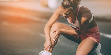 Eine Frau hat Schmerzen nach einer Verletzung und braucht erste Hilfe im Sport.